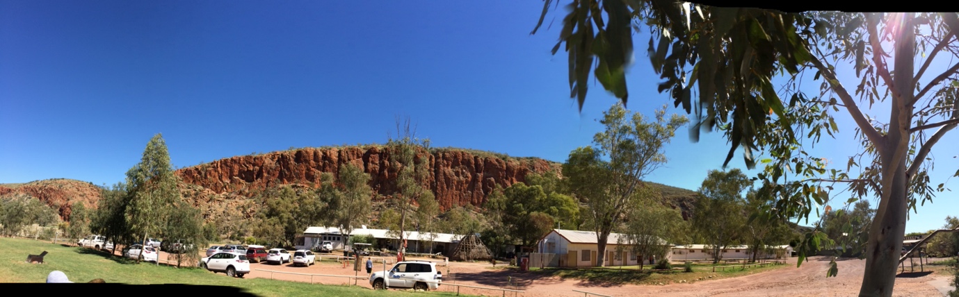 Glen Helen Gorge surrounded by trees with buildings and cars in front.