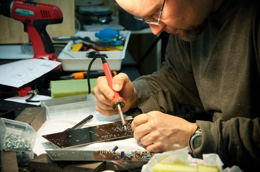 Person soldering circuit board in a workshop