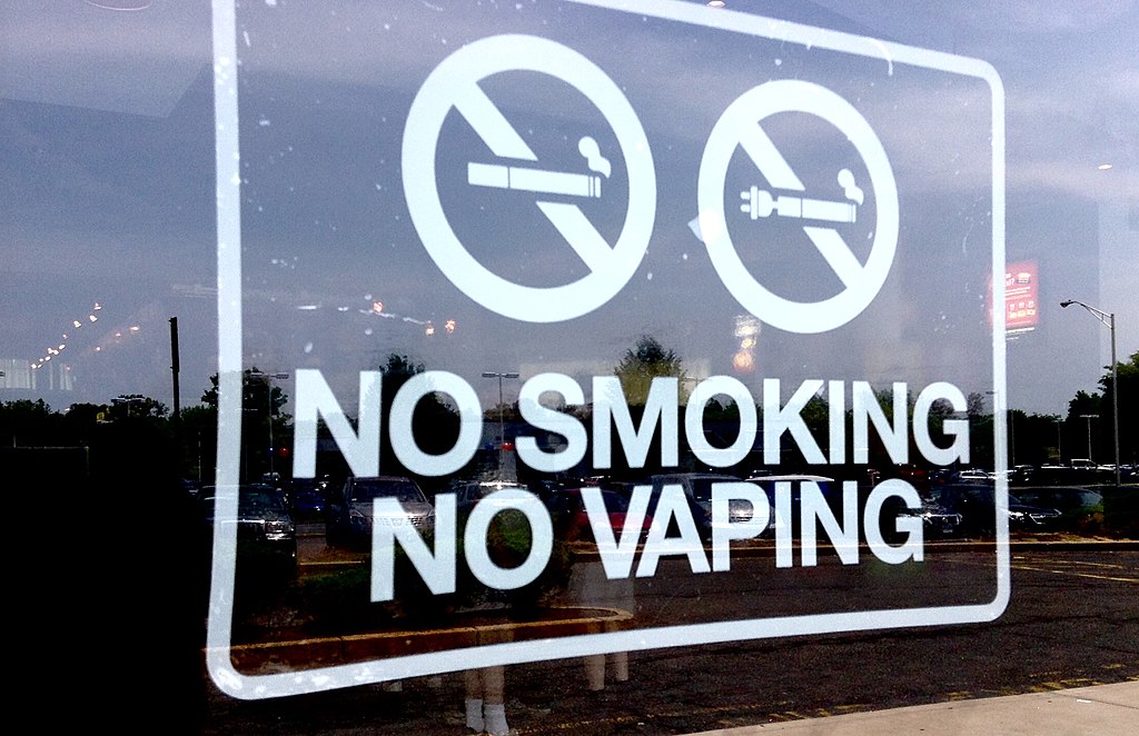An image of a poster in a shop window saying 'No smoking, no vaping'.