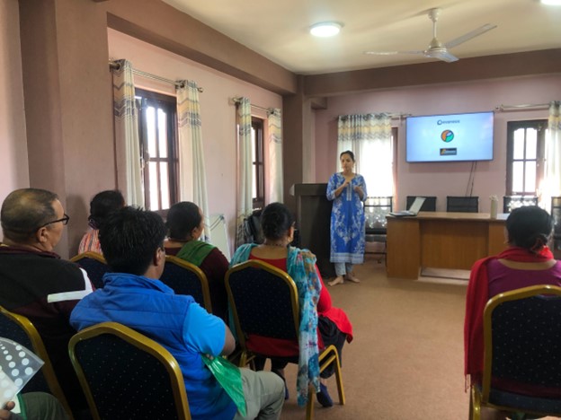 Pushpa presents to a group of community members in a conference room during a tourism product development training session.