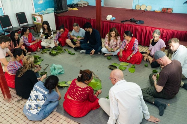 FAM trip participants join local hosts in Nagarkot to make traditional leaf plates, engaging in a hands-on cultural experience.