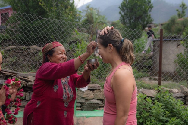Ms. Jagmati Tilija standing at the entrance of her homestay in Narchyang, warmly welcoming arriving guests.