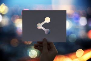 Image of a hand holding up a sign with an image of connecting atoms on it