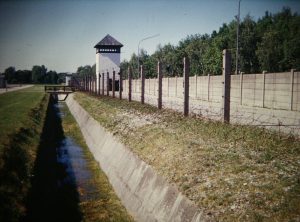 Watch tower with barbed wire fence and trench with grass