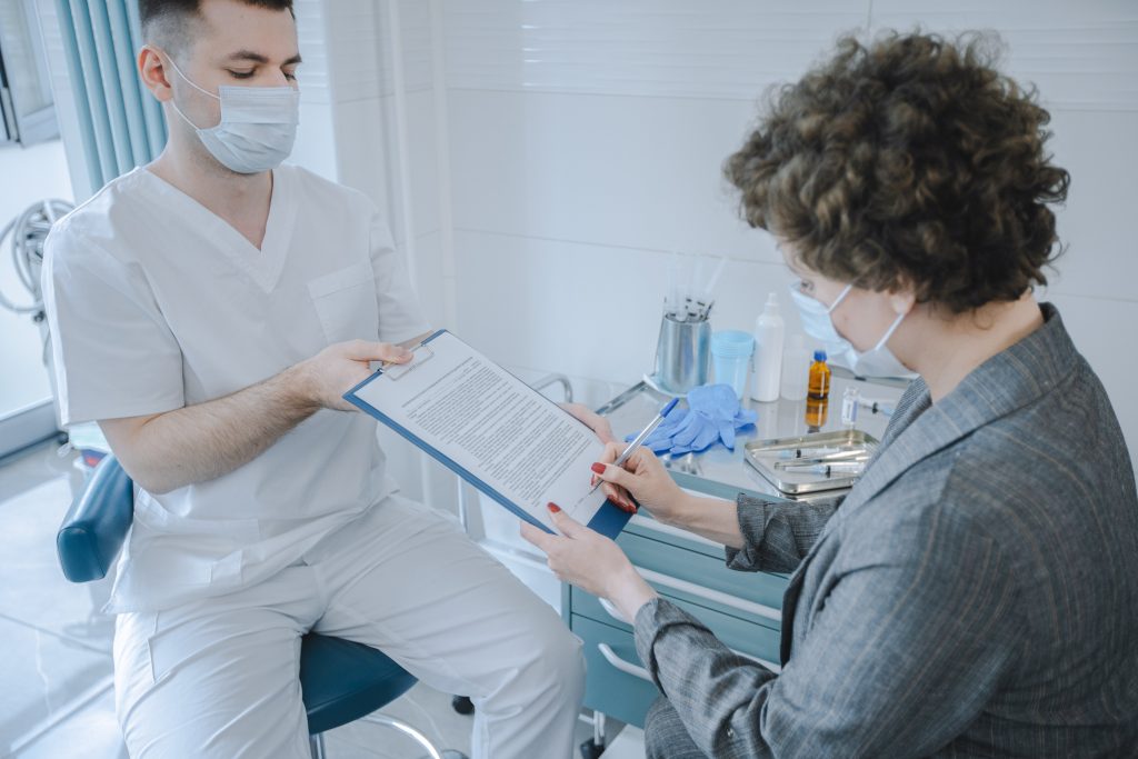 Patient signing document with medical staff watching